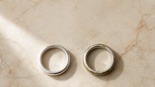 Solid sterling silver ring next to a worn silver plated ring showing brass underneath, on cream marble