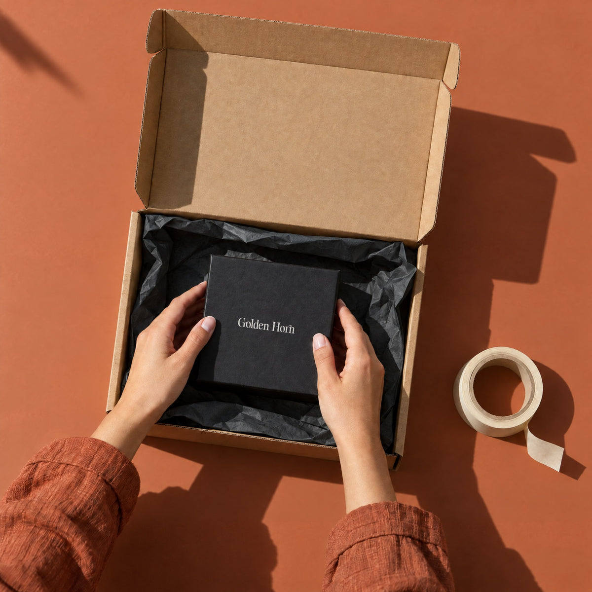 Golden Horn gift box being packed into a kraft mailer with tissue paper