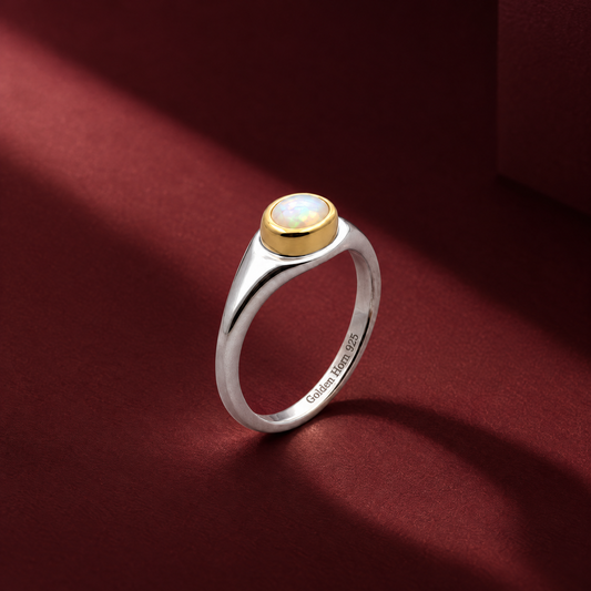 Golden Horn October Opal Birthstone Ring with a silver band and gold-coloured bezel against a burgundy background