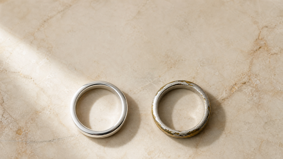 Solid sterling silver ring next to a worn silver plated ring showing brass underneath, on cream marble
