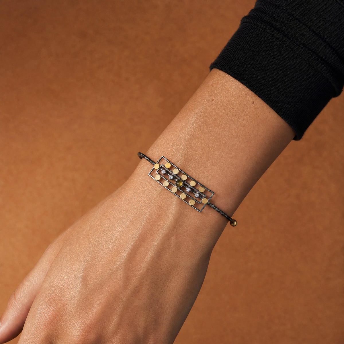 Ancient Queen Gemstone Bracelet worn on the wrist, gold discs and olive tourmaline on oxidised silver – handmade jewellery by Golden Horn