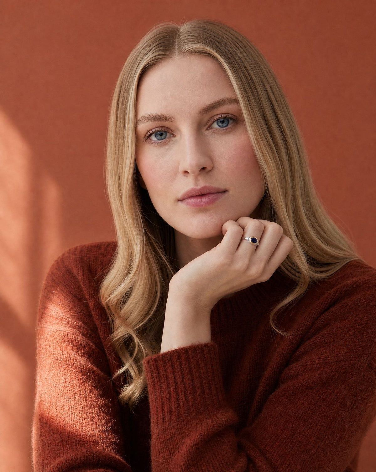 Woman in a rust jumper wearing a Golden Horn sapphire silver ring