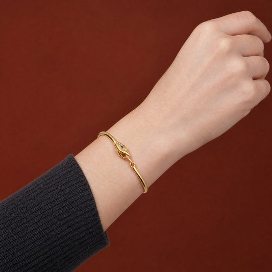 Ouroboros Snake Gold Plated Bracelet worn on the wrist, fastened closed, close-up of the engraved snake head with blue eye – handmade jewellery by Golden Horn